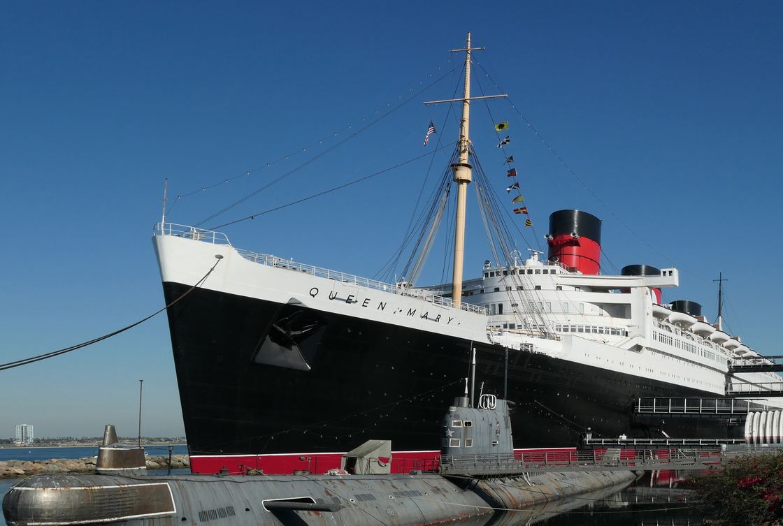 The Queen Mary ocean liner docked in Long Beach, with its three red funnels against a blue sky